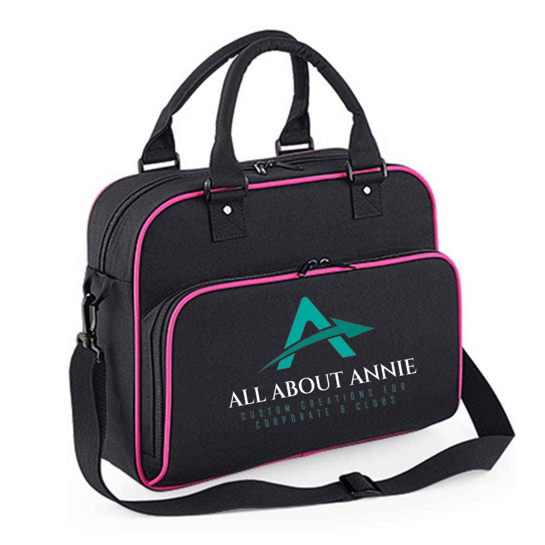 A black Hold-All Bag with 'All About Annie' branding in white and teal on the front. The bag has a zippered closure and an adjustable crossbody strap.